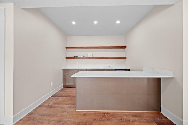 kitchen featuring light countertops, a peninsula, open shelves, and light wood-style floors