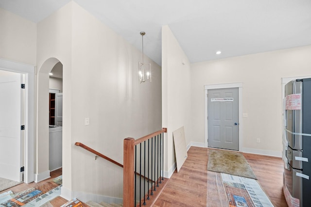 foyer featuring arched walkways, recessed lighting, wood finished floors, a chandelier, and baseboards