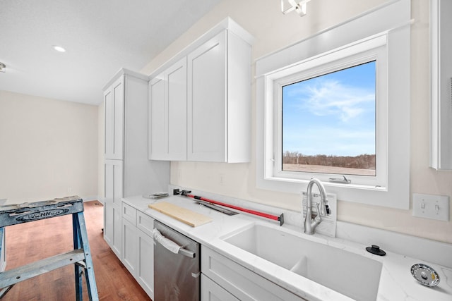 kitchen featuring a sink, white cabinetry, stainless steel dishwasher, and wood finished floors