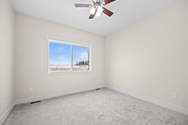 carpeted spare room featuring ceiling fan, visible vents, and baseboards