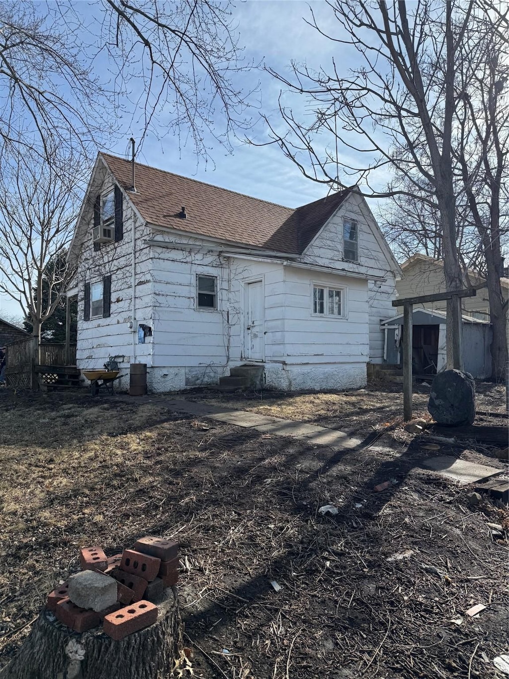 view of side of home with entry steps and a shingled roof