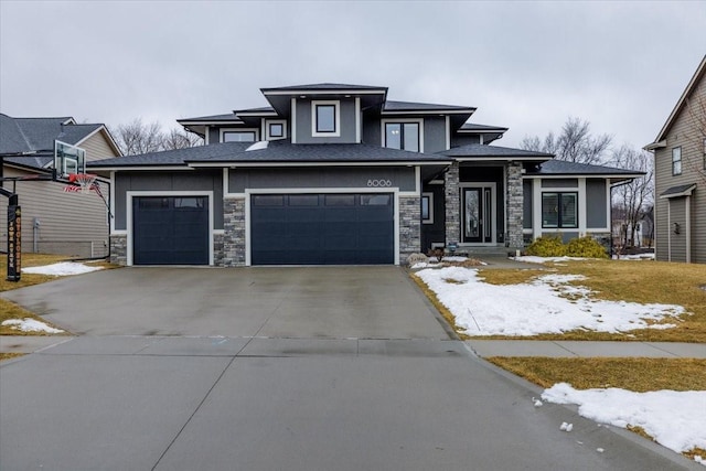 prairie-style house with stone siding, an attached garage, and concrete driveway