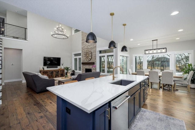 kitchen featuring dishwasher, blue cabinetry, dark wood-style floors, and a sink