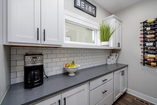 bar featuring decorative backsplash, baseboards, visible vents, and dark wood-style flooring