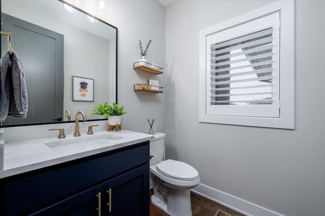 bathroom featuring vanity, toilet, wood finished floors, and baseboards