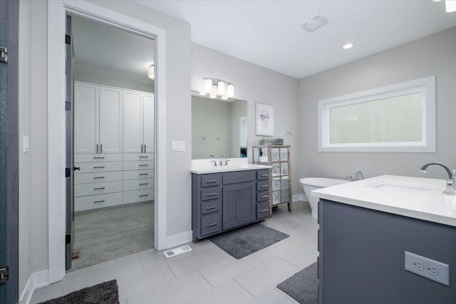 full bathroom featuring a sink, visible vents, a soaking tub, and two vanities