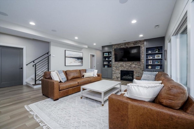 living area with visible vents, recessed lighting, stairway, light wood-style floors, and a stone fireplace