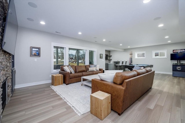 living area with recessed lighting, baseboards, a fireplace, and light wood finished floors