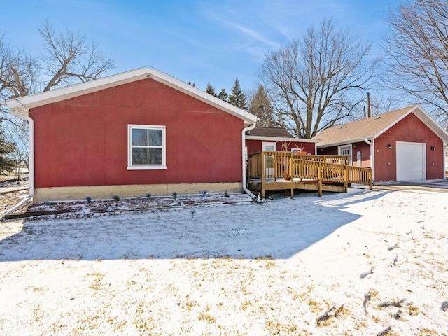 view of snowy exterior with a garage and a deck