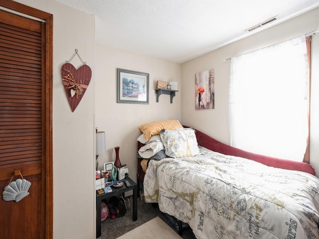 bedroom with a textured ceiling, a closet, carpet flooring, and visible vents