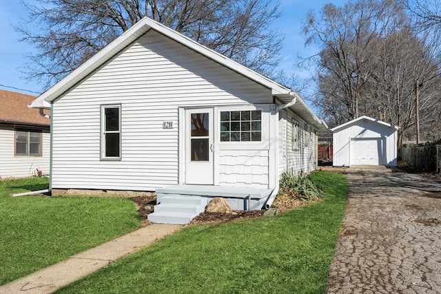 bungalow-style house featuring a garage, aphalt driveway, an outdoor structure, and a front yard