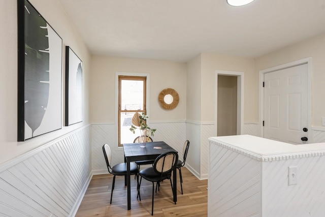 dining space featuring light wood-type flooring and wainscoting