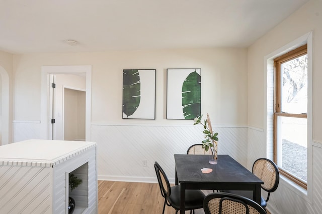 dining area with light wood finished floors and wainscoting