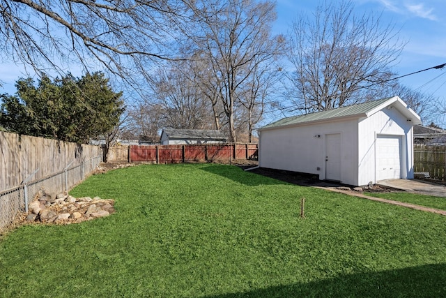 view of yard with a fenced backyard, a detached garage, and an outdoor structure