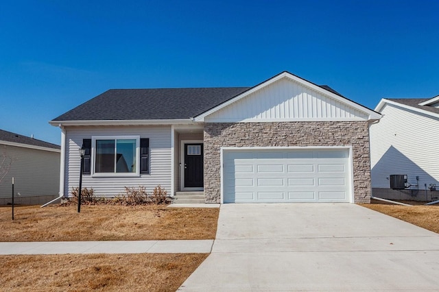 ranch-style home with a garage, driveway, stone siding, roof with shingles, and central AC