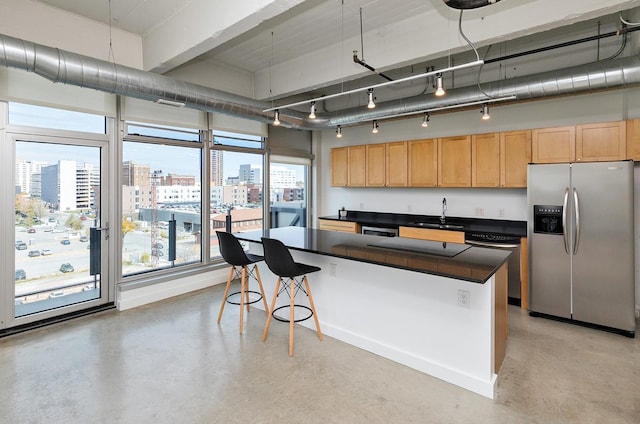 kitchen featuring dark countertops, a city view, concrete flooring, dishwashing machine, and stainless steel refrigerator with ice dispenser