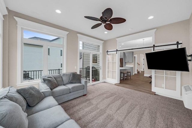 living room with ceiling fan, carpet floors, a barn door, and recessed lighting