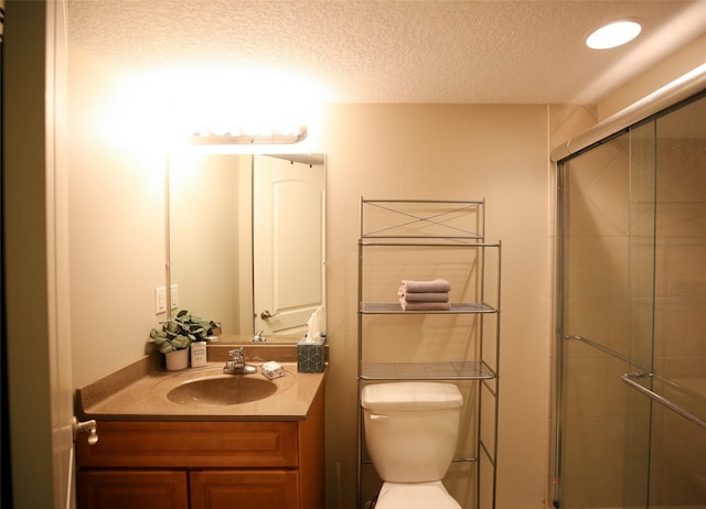 bathroom featuring a stall shower, a textured ceiling, toilet, and vanity