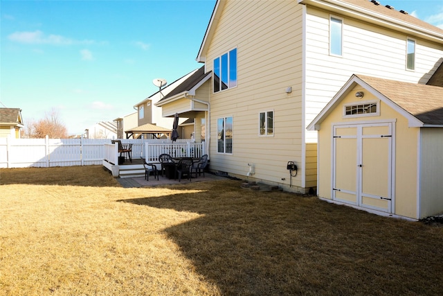 rear view of property with a yard, a shed, fence, and an outbuilding