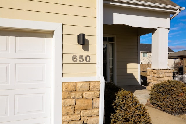 property entrance with a garage and stone siding