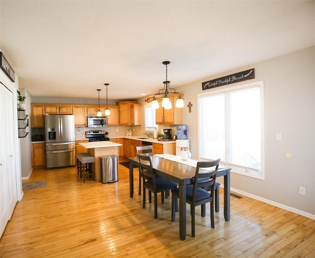 dining space with light wood finished floors, visible vents, and baseboards