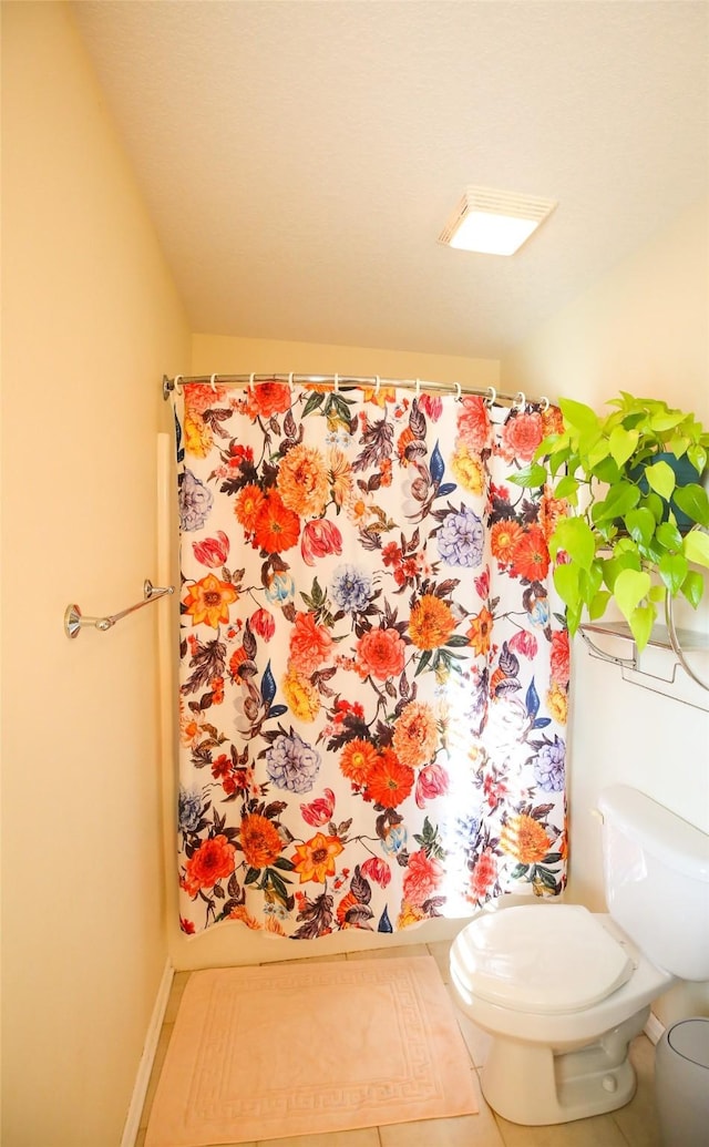 full bath featuring curtained shower, toilet, and baseboards