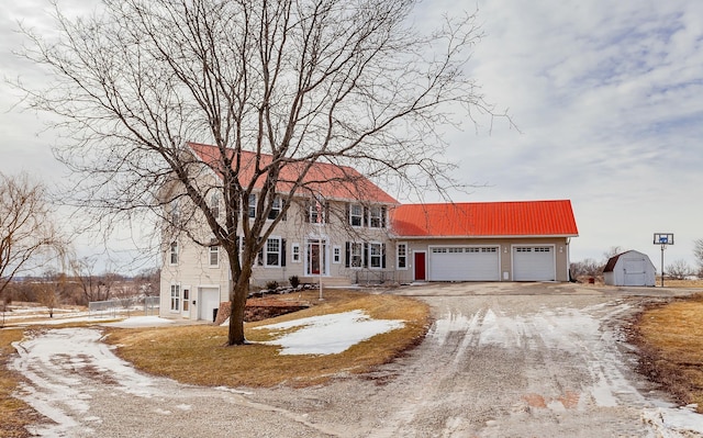 colonial inspired home with an attached garage, a storage shed, and dirt driveway