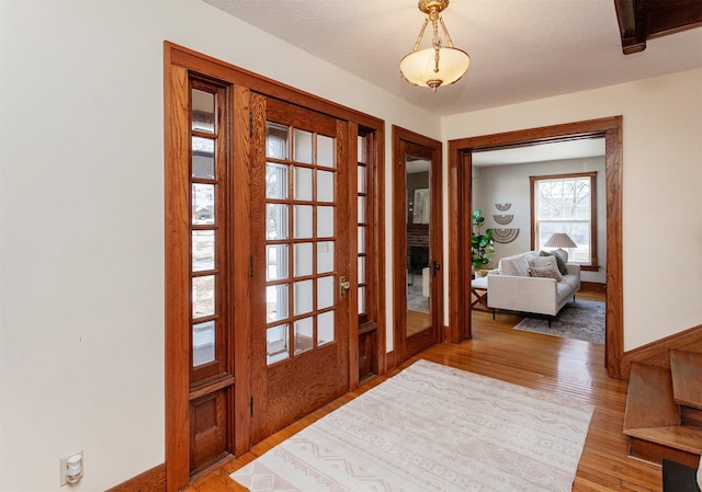 foyer entrance with baseboards, light wood-style flooring, and a textured ceiling