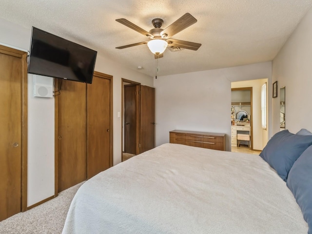 bedroom with a ceiling fan, multiple closets, and a textured ceiling