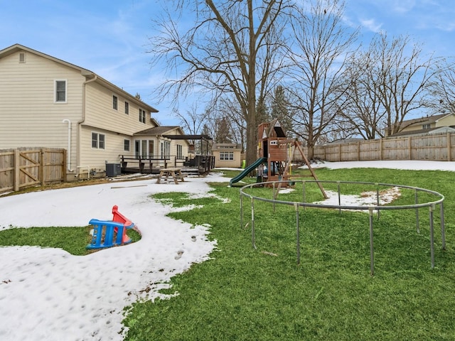 view of yard featuring a fenced backyard, a deck, a playground, and central AC