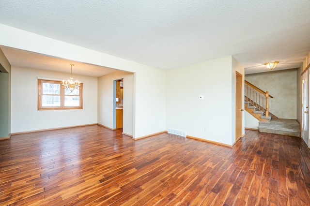 unfurnished living room with visible vents, stairway, a textured ceiling, a chandelier, and hardwood / wood-style flooring