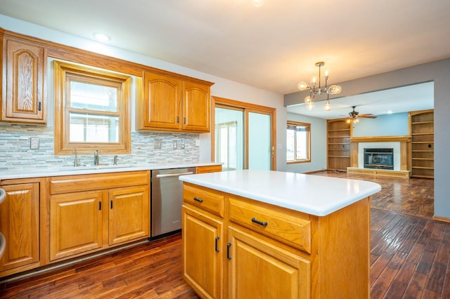 kitchen featuring dark wood-style flooring, a sink, open floor plan, dishwasher, and a glass covered fireplace