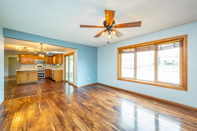 unfurnished living room with baseboards, dark wood-style flooring, and ceiling fan with notable chandelier