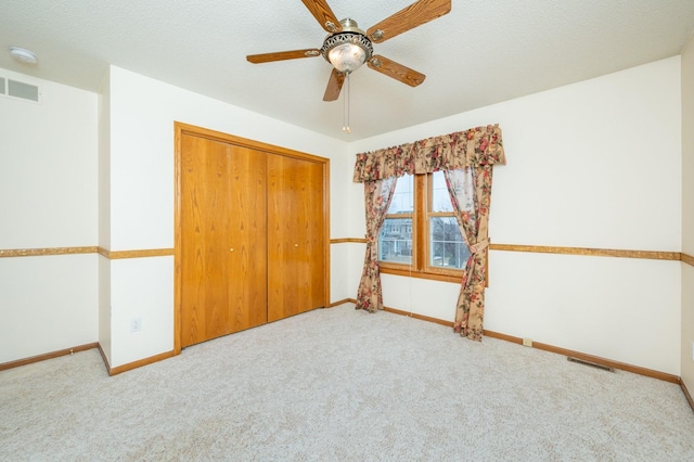 unfurnished bedroom featuring carpet floors, a closet, visible vents, a textured ceiling, and baseboards