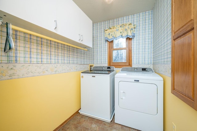 washroom featuring a textured ceiling, washing machine and dryer, cabinet space, and wallpapered walls