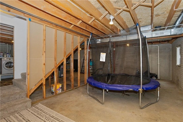 basement featuring brick wall and washer / clothes dryer