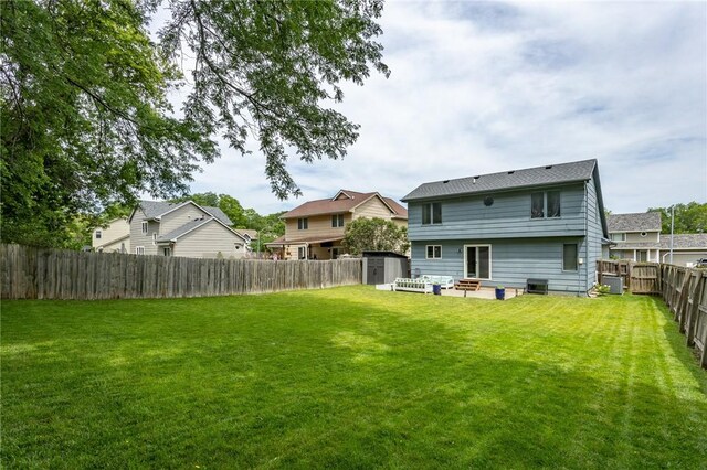 back of property with an outbuilding, a fenced backyard, a yard, and a storage unit