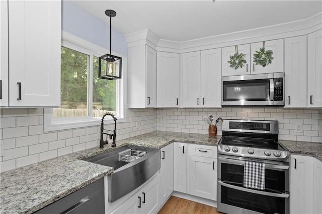 kitchen featuring tasteful backsplash, white cabinetry, stainless steel appliances, and a sink
