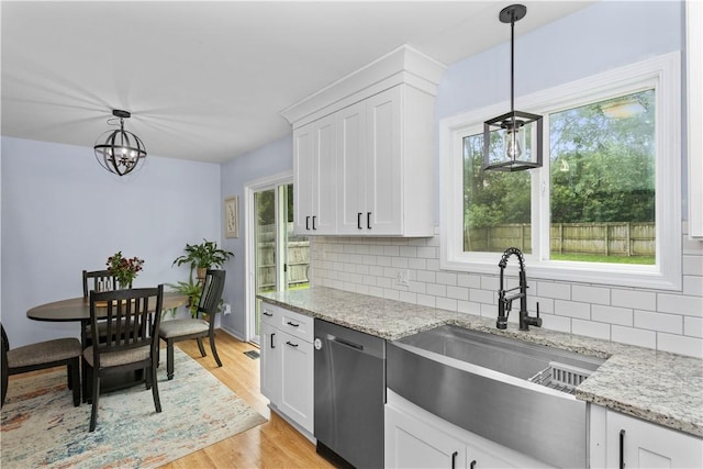 kitchen with a wealth of natural light, light wood-style flooring, white cabinets, a sink, and dishwasher