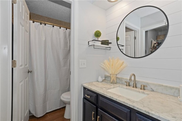 full bath featuring toilet, a shower with curtain, wood finished floors, a textured ceiling, and vanity