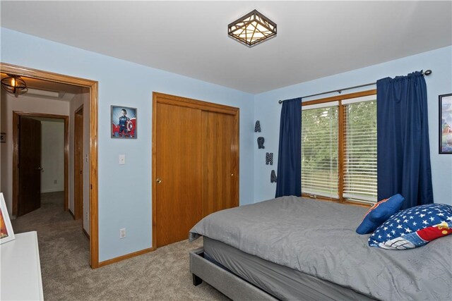 carpeted bedroom featuring a closet and baseboards
