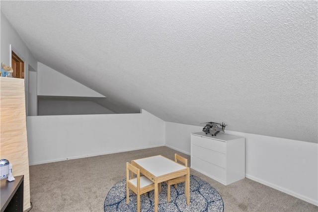 interior space featuring lofted ceiling, carpet flooring, a textured ceiling, and baseboards