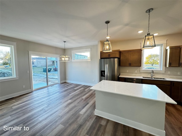 kitchen featuring stainless steel fridge, baseboards, dark wood-style flooring, pendant lighting, and a sink