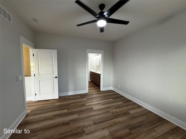 unfurnished bedroom with visible vents, dark wood finished floors, ensuite bath, and baseboards