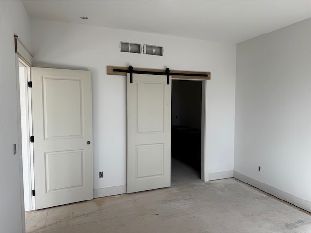 unfurnished bedroom featuring a barn door and baseboards