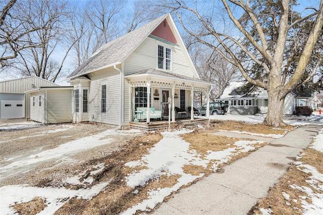 view of front of home featuring covered porch, a shingled roof, and a garage