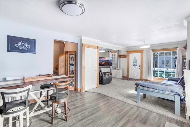 living area with crown molding, stairway, wood finished floors, and baseboards