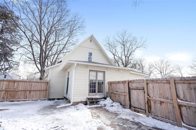 snow covered rear of property with entry steps and a fenced backyard