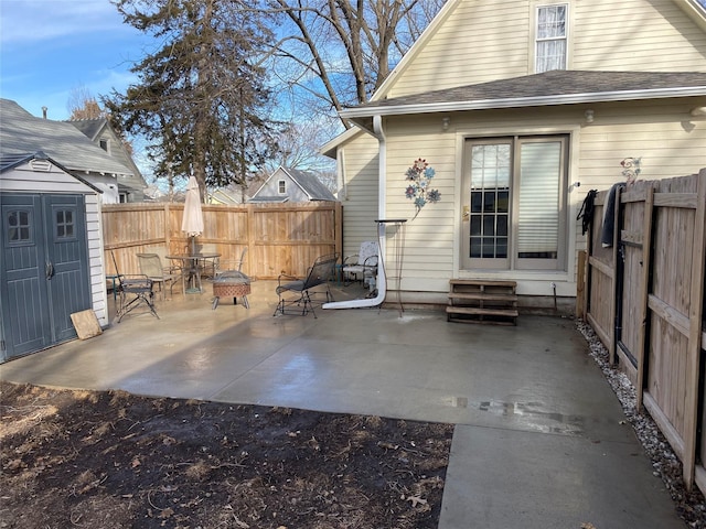 rear view of house with a patio area, entry steps, a storage shed, a fenced backyard, and an outbuilding