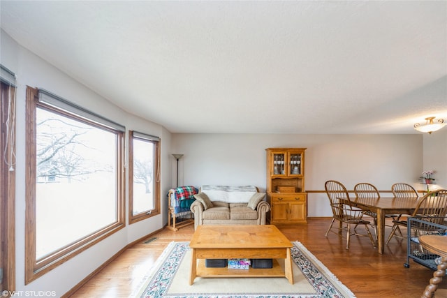 living room featuring light wood-type flooring, visible vents, and baseboards